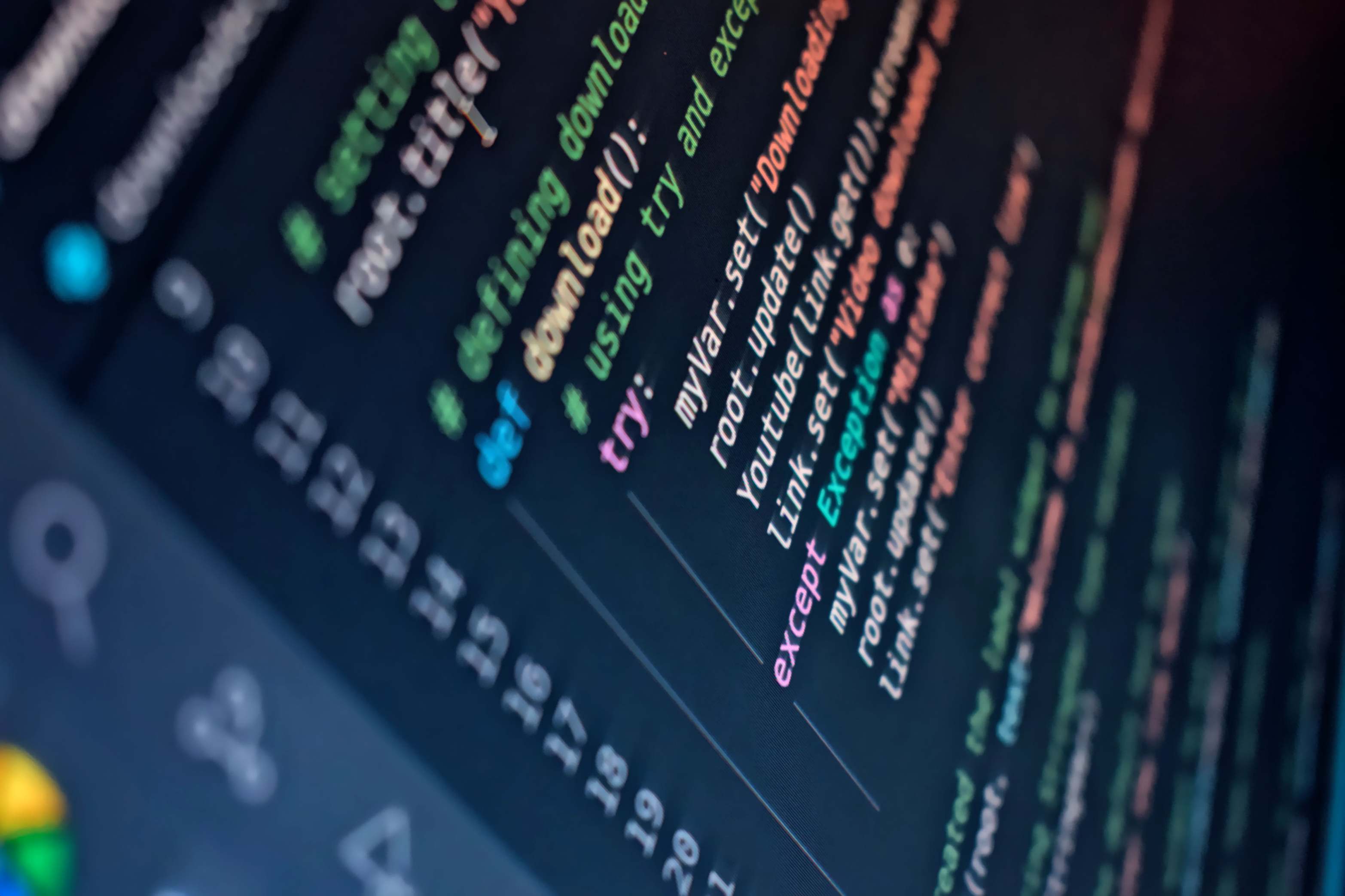 Software development workspace shown on a wide monitor with colorful programming code on screen